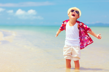 happy fashionable kid boy enjoys life on summer beach