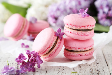 Obraz na płótnie Canvas French pink macarons with lilac flowers on white wooden backgrou