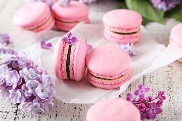 French pink macarons with lilac flowers on white wooden backgrou