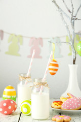 Easter cookies with bottle of milk on white wooden background