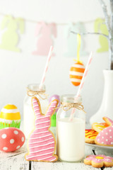 Easter cookies with bottle of milk on white wooden background