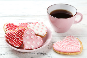 Heart cookies with cup of coffee on white wooden background