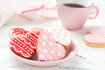 Heart cookies with cup of coffee on white wooden background