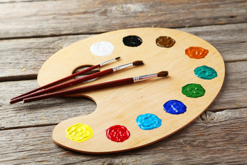 Wooden art palette with paints on grey wooden background