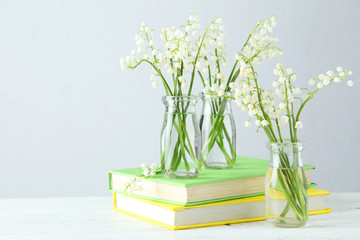 Lily of the Valley in bottles on white wooden background
