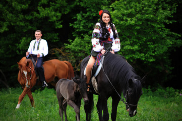 Fototapeta premium Young couple on national dress with horses