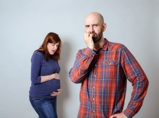 Unsicherer Mann, schwangere Frau mit Schmerzen im Hintergrund - obrazy, fototapety, plakaty