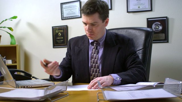 Overwhelmed businessman signing papers and being placed on his desk in the inbox