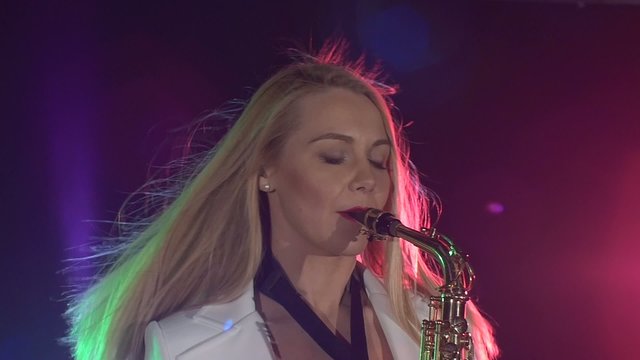 Young sexy, blonde woman dj in white jacket playing music using