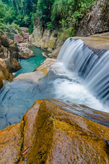 Jungle waterfall with flowing water, large rocks © Biskariot