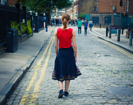 Young woman walking on cobbled street in summer