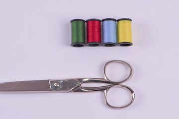 Thread green, red, blue, and yellow with scissors.