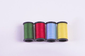 Threads of green, red, blue, and yellow on a white background