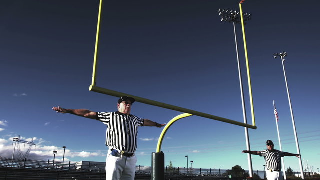 Two referees wave their arms back and forth after a missed field goal