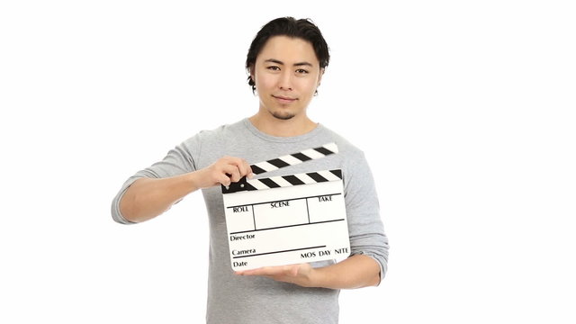 A man wearing a grey shirt holding a movie slate 