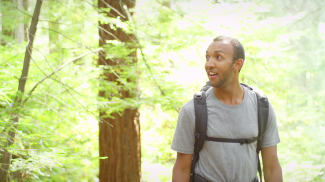 A man hiking on a forest trail stops to take a picture with his phone