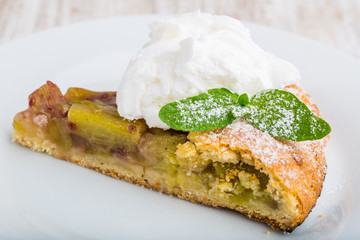 Piece of sweet cake with rhubarb and whipped cream