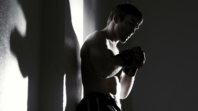 A fighter shadow boxes while a bright light shines on him in the dark