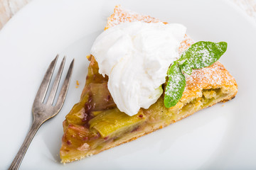 Piece of sweet cake with rhubarb and whipped cream