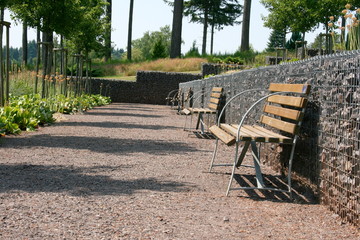 A wooden bench in front of a stone wall

