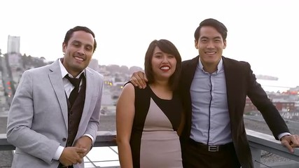 Two men and a woman in formal dress stand on a rooftop and smile into the camera - Powered by Adobe