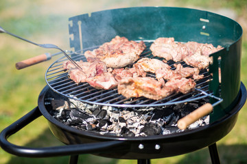 barbecue pork meat cooking outdoors on a portable grill