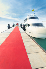 Yacht docking at the pier with red carpet to party