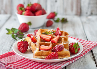 Belgium waffles with strawberries and mint on white plate