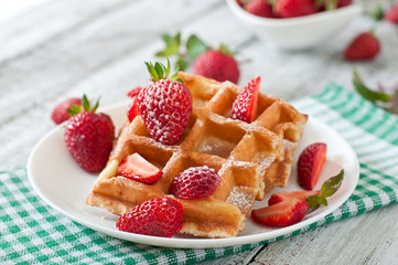 Belgium waffles with strawberries and mint on white plate