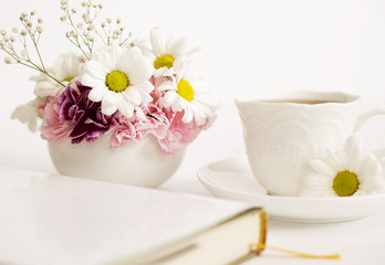 Fototapeta na wymiar Bouquet of beautiful flowers with a cup and book