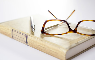 Fountain pen and glasses on book