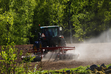 Fototapeta premium Old tractor plowing at sunset, sweden