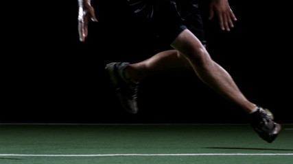 A male athlete runs back and forth between some cones
