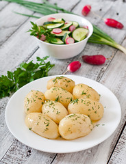 Young boiled potatoes with butter and dill on a white plate