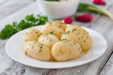 Young boiled potatoes with butter and dill on a white plate