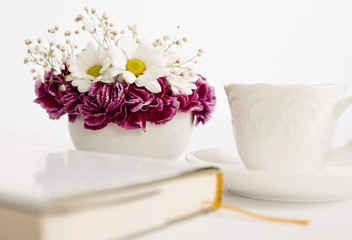 Bouquet of beautiful flowers with a cup and book