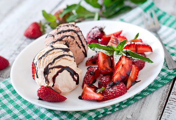 Ice cream with strawberries and chocolate on a white plate