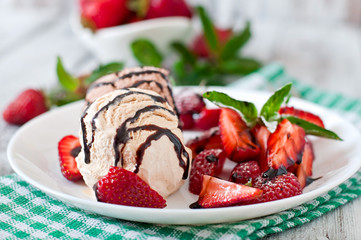 Ice cream with strawberries and chocolate on a white plate