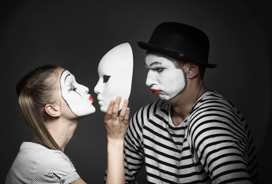 Female mime kissing the mask of male mime
