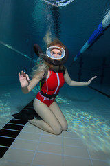Female scuba diver with red swimsuit diving in the pool 