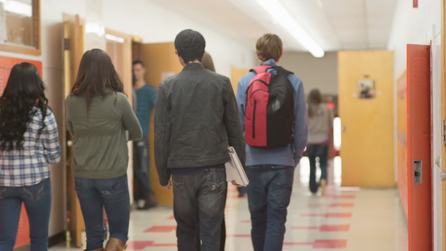 Students walk away from the camera down the hallway to their next classes