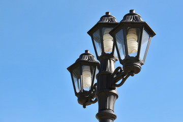 Fototapeta na wymiar Three vintage street lamps against bright blue sky