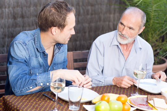 Vater und Sohn unterhalten sich im Garten beim Essen