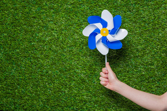 Hand Holding Pinwheel Over Green Grass