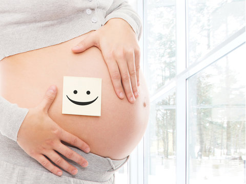 Young, healthy and happy pregnant woman with a sticker on her belly