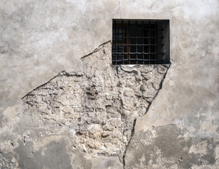 barred window in a crumbling concrete wall