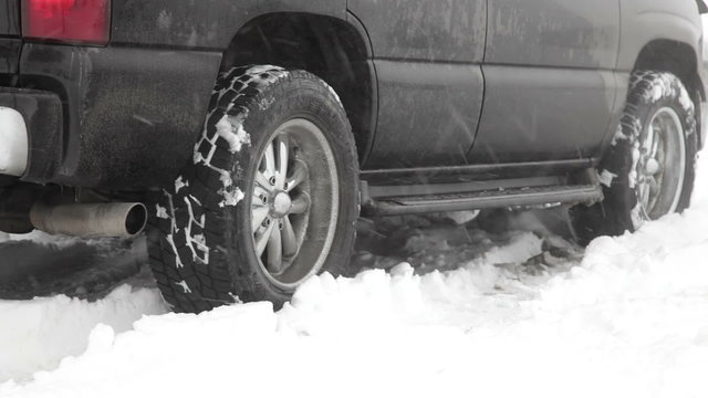 Close up shot of black SUV backing up in the snow