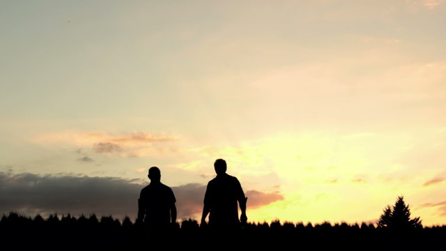 Silhouette Of Two Golfers Walking Toward The Camera. 