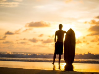 Surfer on the ocean beach at sunset on Bali island
