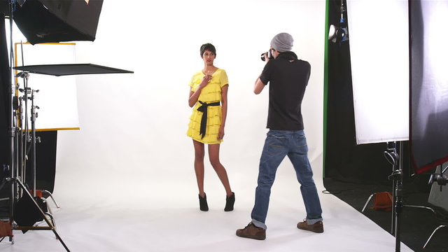 Behind the scenes footage of a model in a yellow dress being photographed on a large white background with big lights